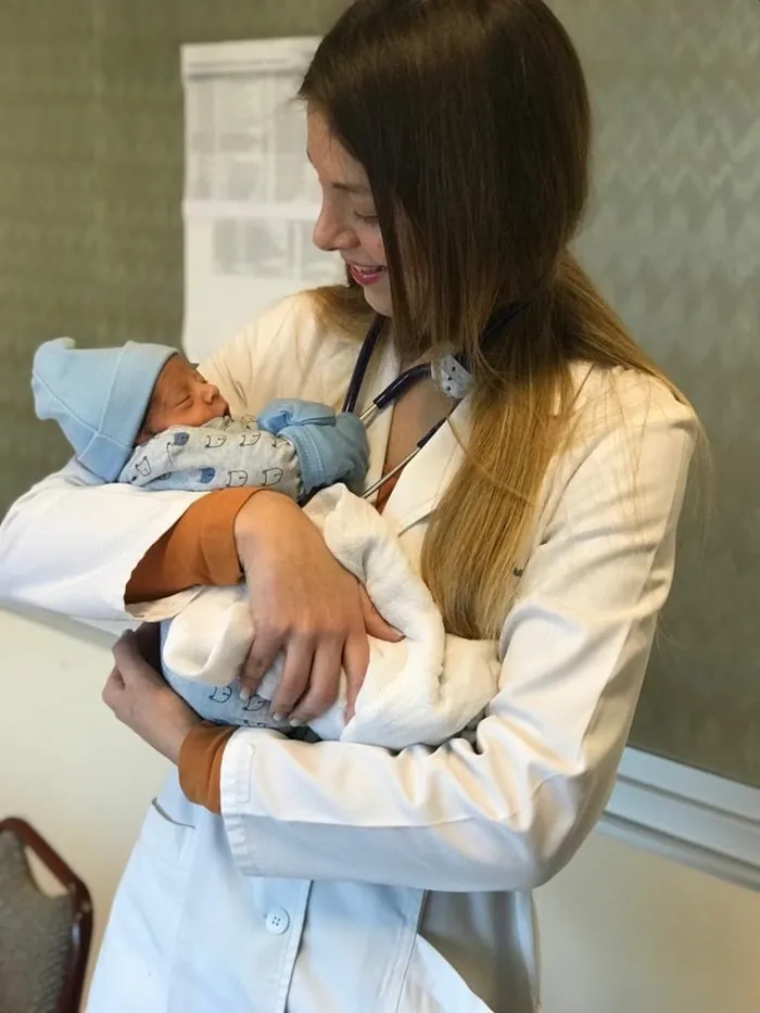 La doctora sosteniendo a un recién nacido en brazos